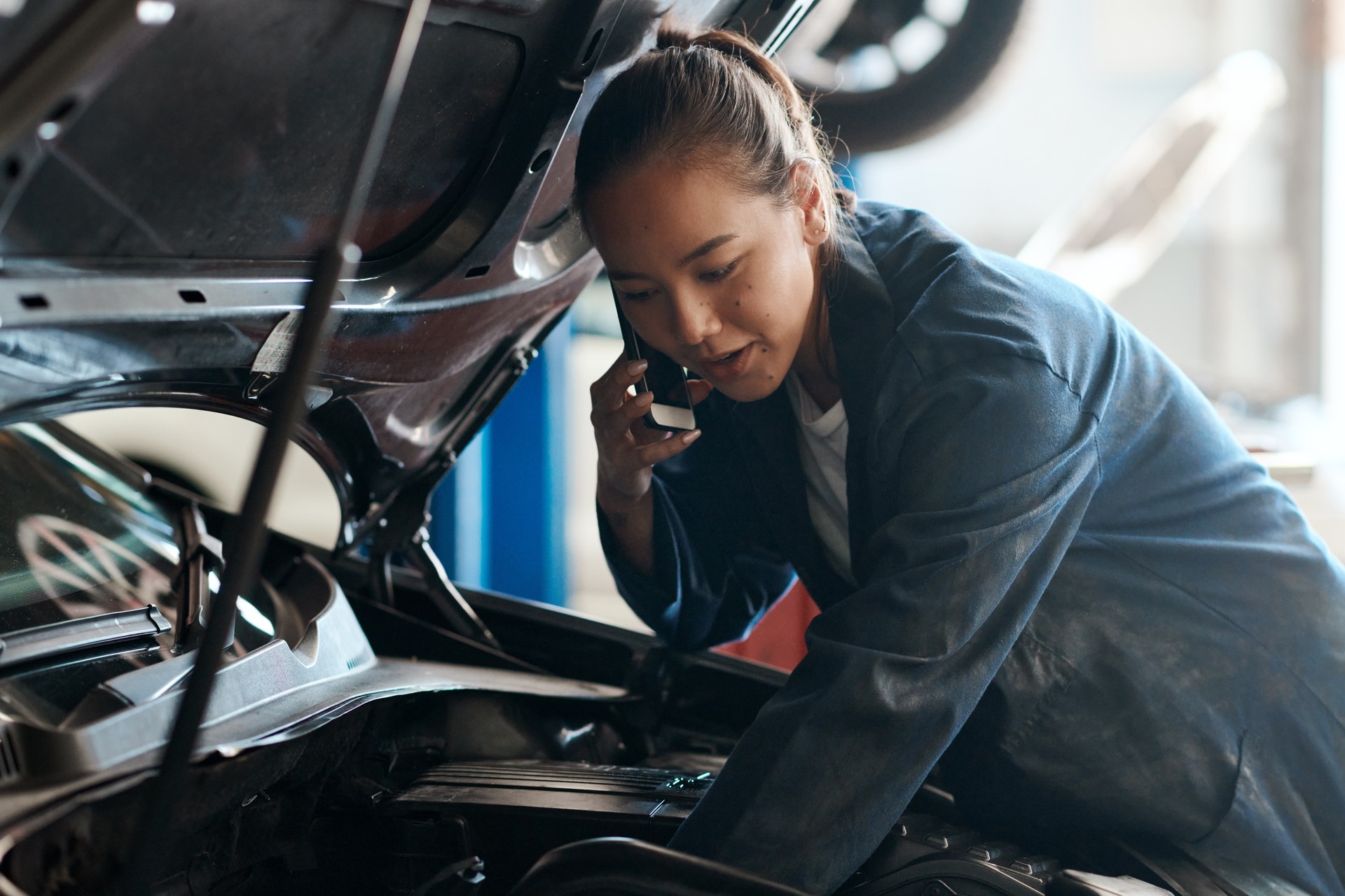 Shot of a female mechanic talking on her cellphone while working in an auto repair shop